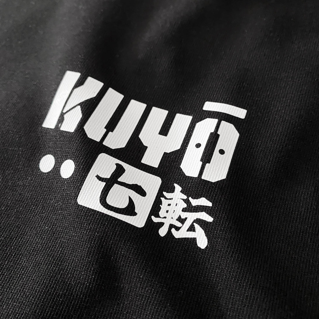 Daruma kuyō- a close-up of a text graphic design, printed on the left chest of a black sweatshirt
