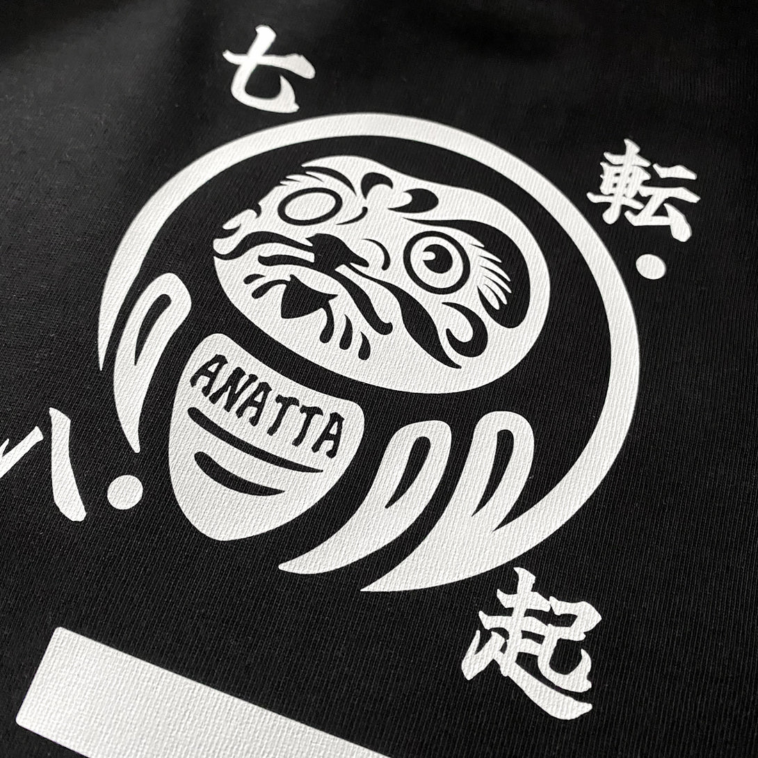 Daruma kuyō - a close-up of the design of daruma doll, printed on the back of a black sweatshirt 