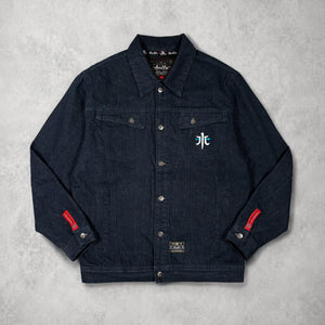 Front view of the Rogue Wave denim jacket featuring heavyweight cotton denim, chest embroidery, and red sleeve labels.