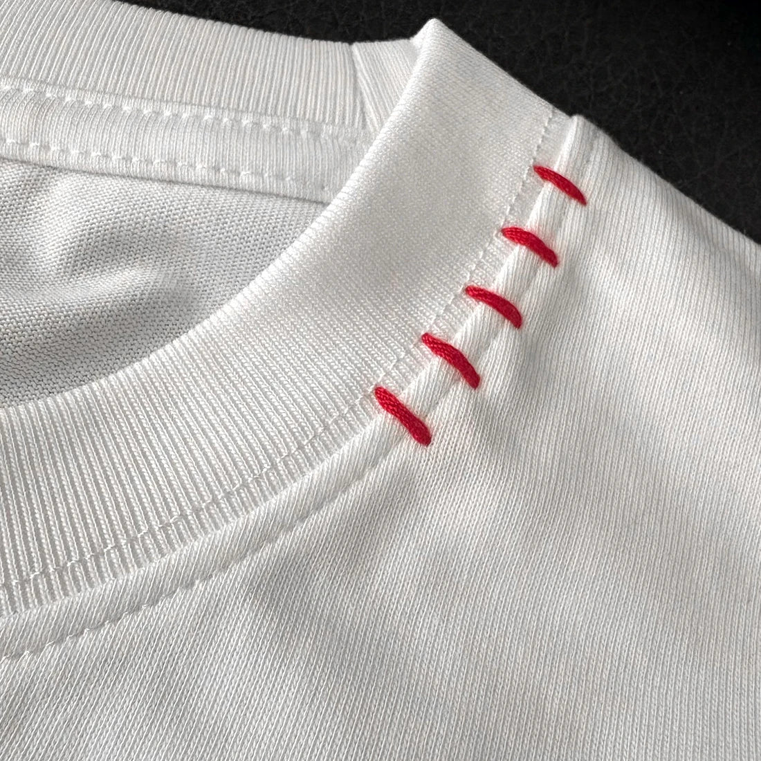 Close-up of a white garment with red stitching detail