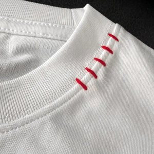Close-up of a white garment with red stitching detail