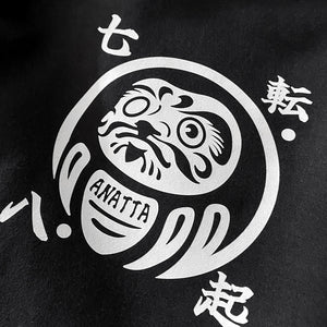 a close-up of a graphic design of a Japanese daruma doll, printed on the left of a Japanese style black shorts-Anatta Streetwear