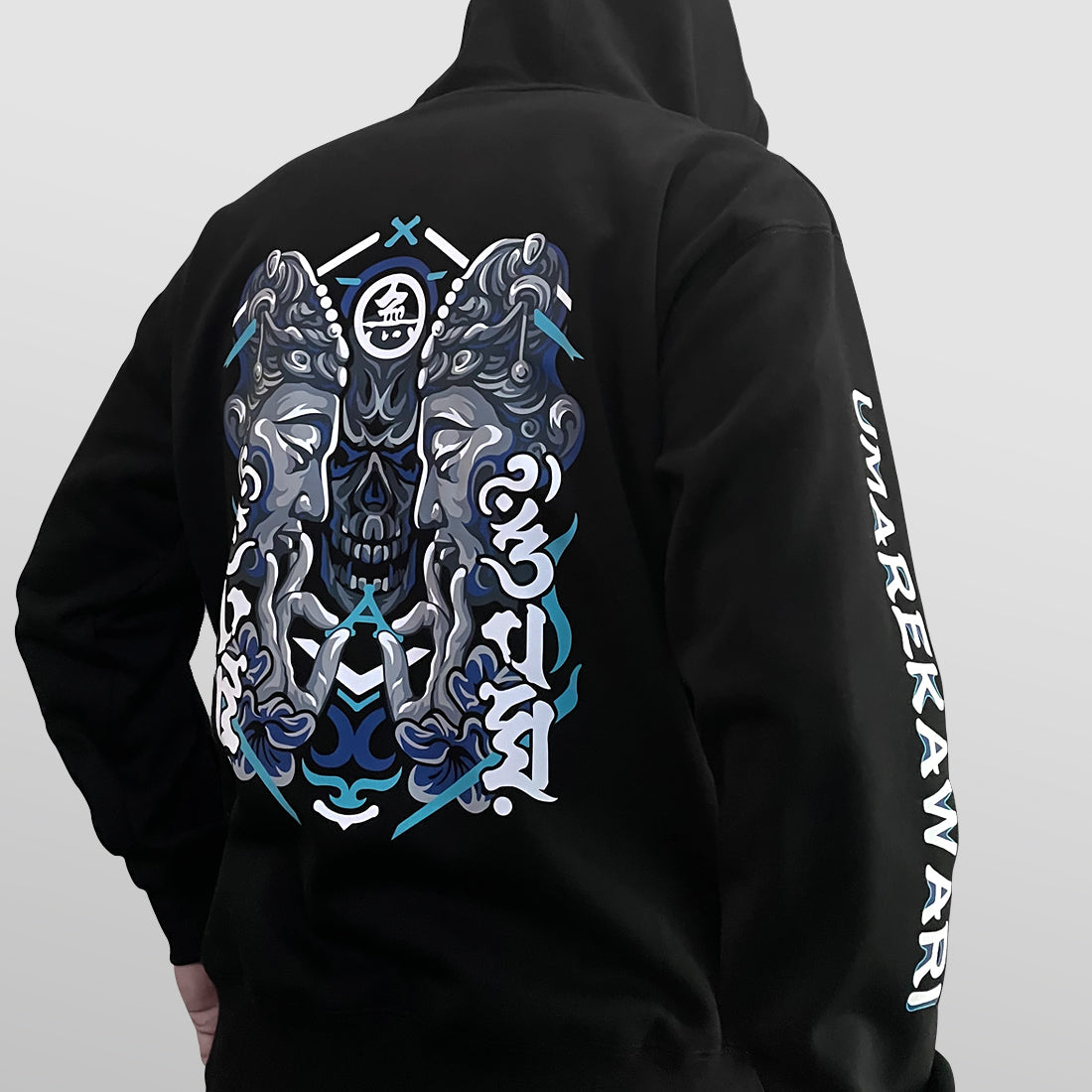 Umarekawari - a model wearing a black hoodie with the design of Buddhas confronting the evil illustration printed on the back-back view - Anatta Streetwear
