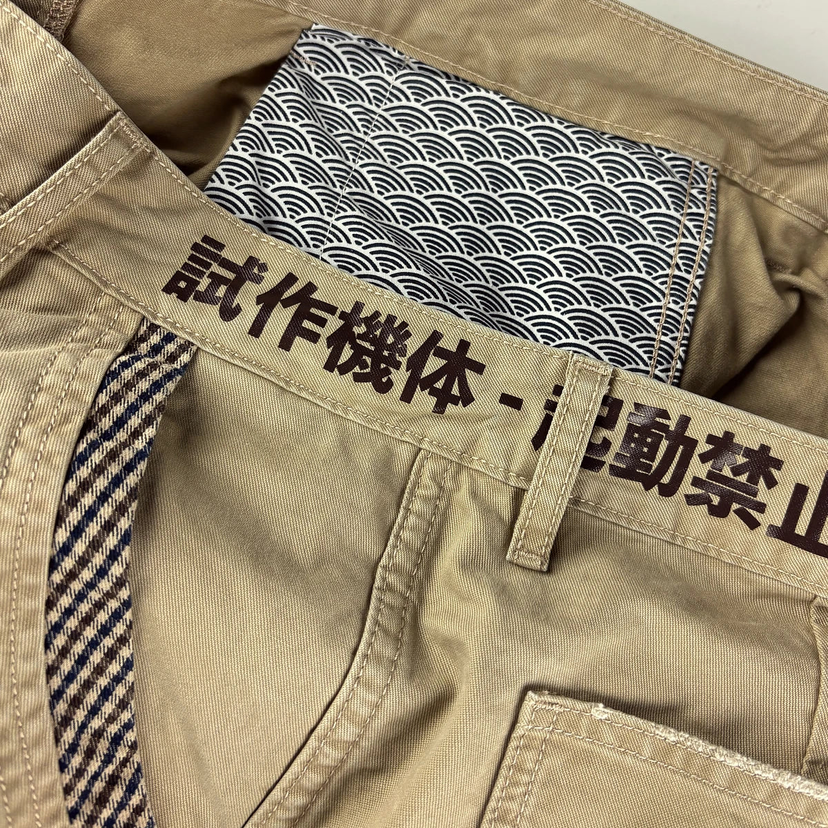 Close-up of khaki cargo pants featuring text printed around the waistband.