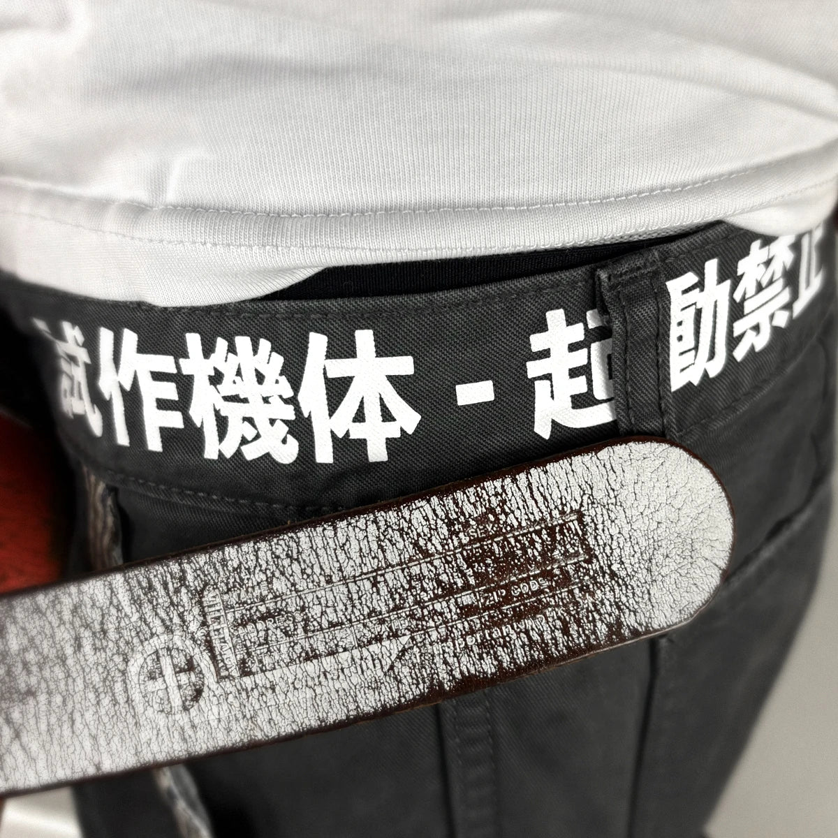 Close-up of dark grey cargo pants featuring text printed around the waistband - Anatta Streetwear
