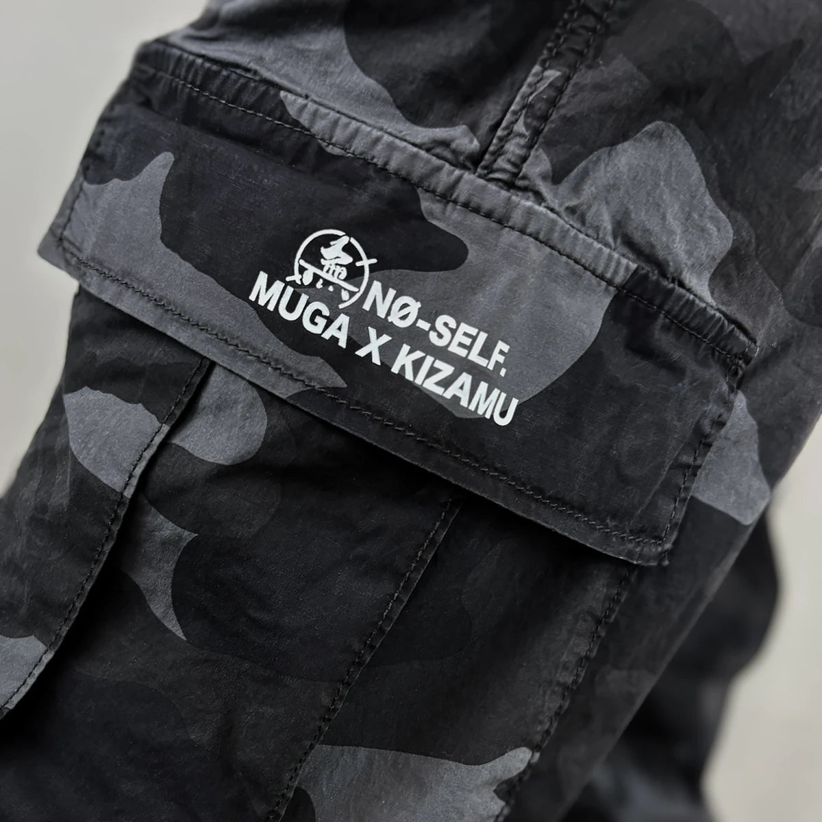 Black camouflage pants with a design printed on the pocket - Anatta Streetwear