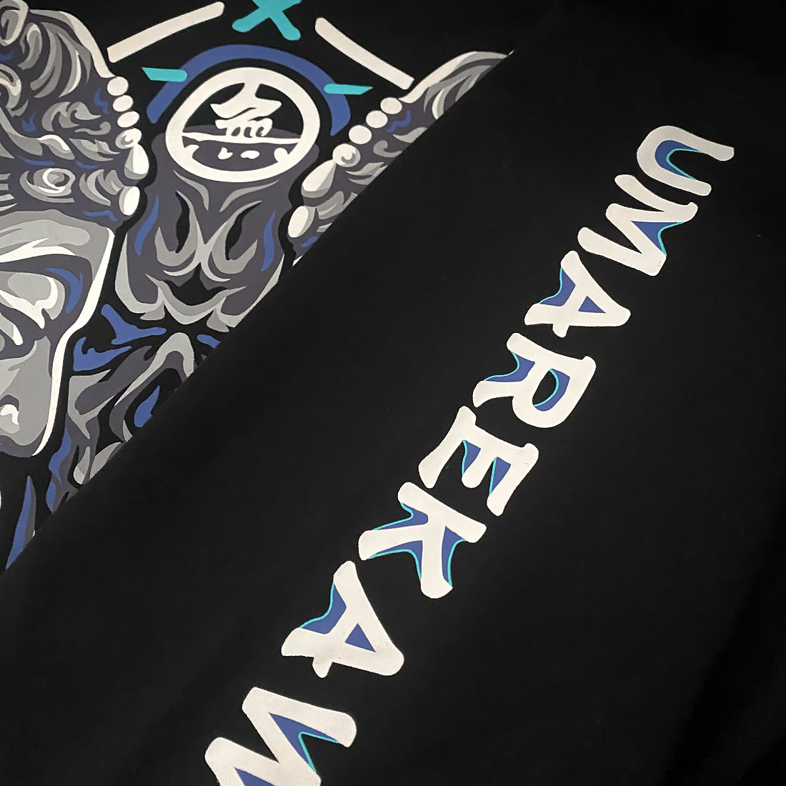 Umarekawari - a close-up of the graphic designs printed on the sleeve of the Japanese style black hoodie - Anatta Streetwear