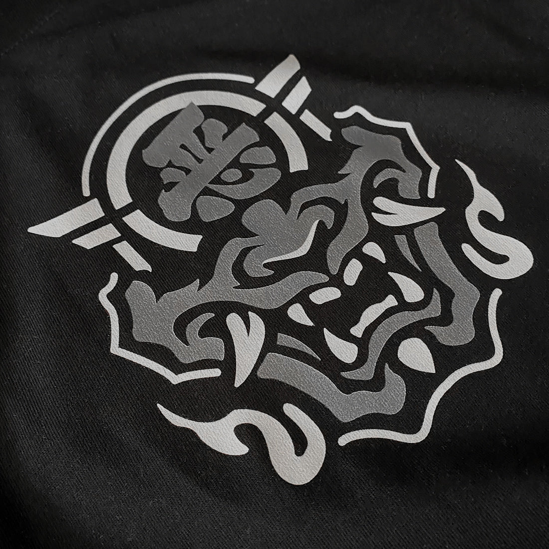 a graphic design of the Japanese Hannya mask, printed on the front of a black tank top