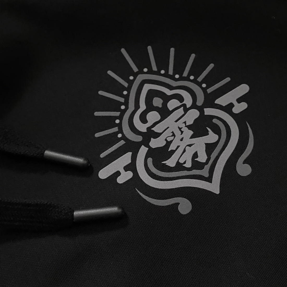 a close-up of a small graphic design, printed on the left chest of the Japanese style black hoodie - Anatta Streetwear