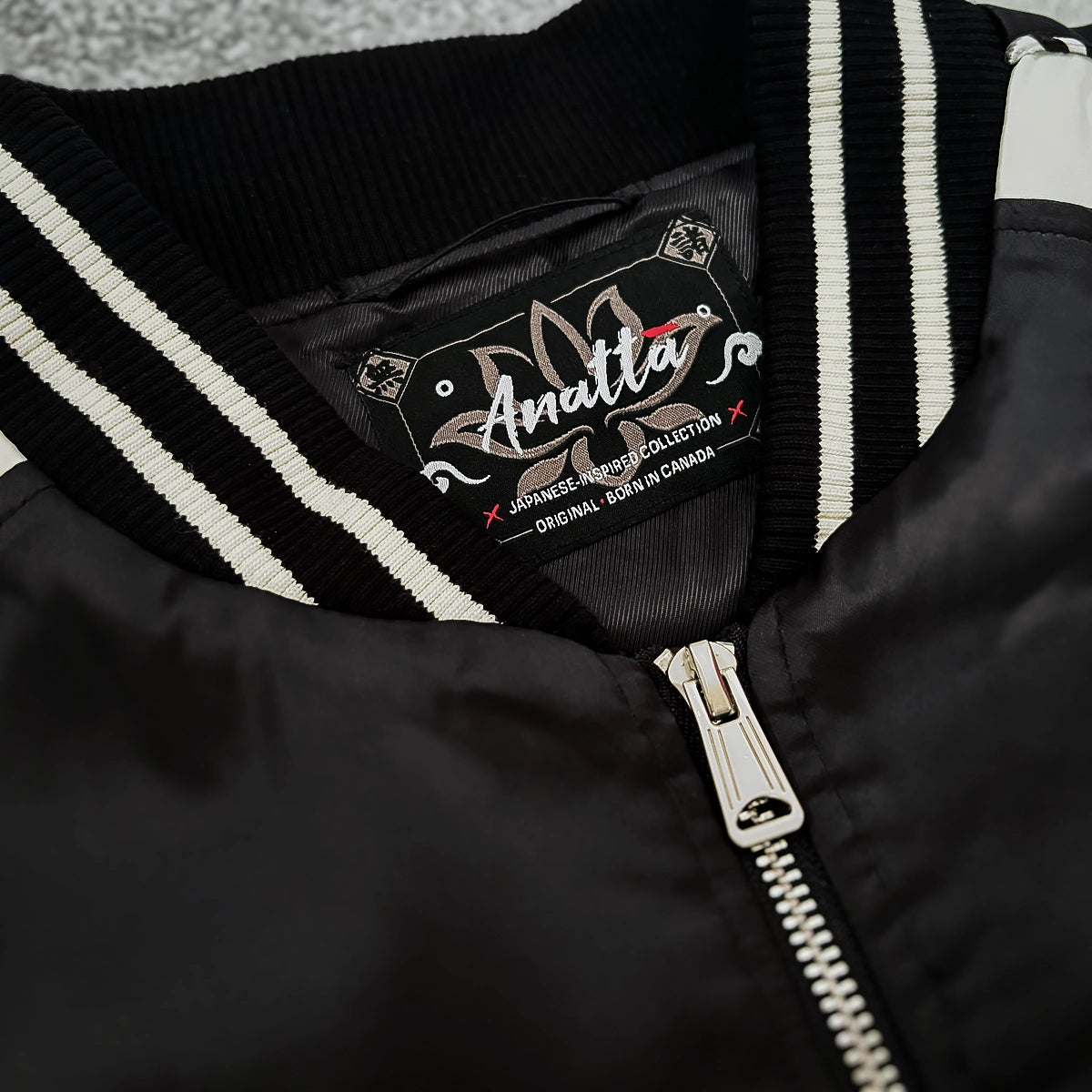 Close-up of the Raijin’s Wrath Japanese satin jacket collar, showing the striped ribbed trim, zipper, and Anatta woven label