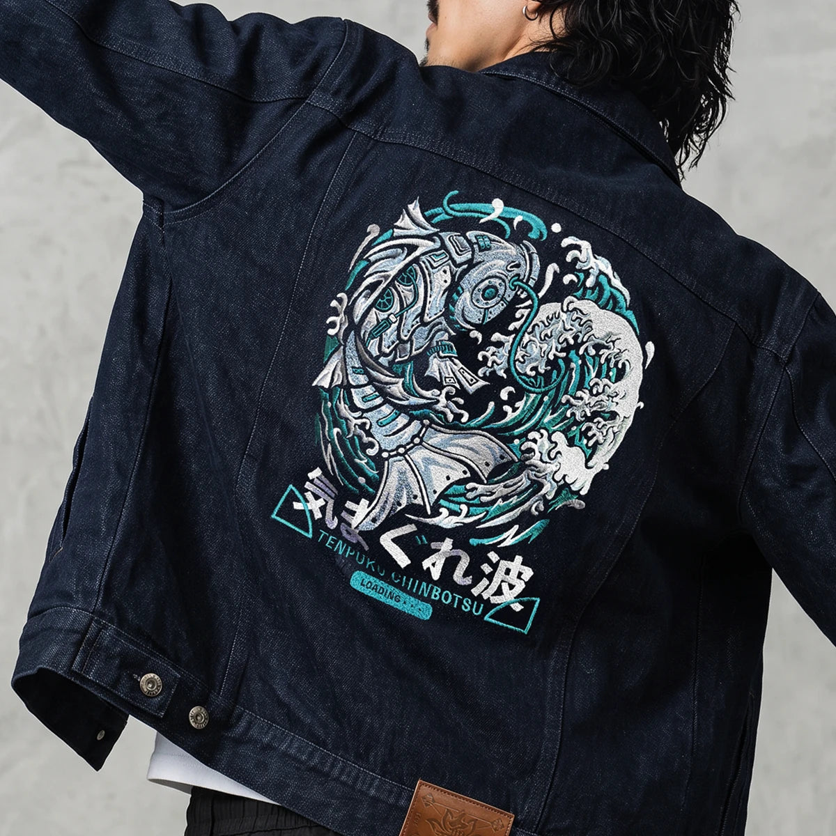 Model wearing the Rogue Wave denim jacket from the back, highlighting the oversized Japanese wave embroidery.