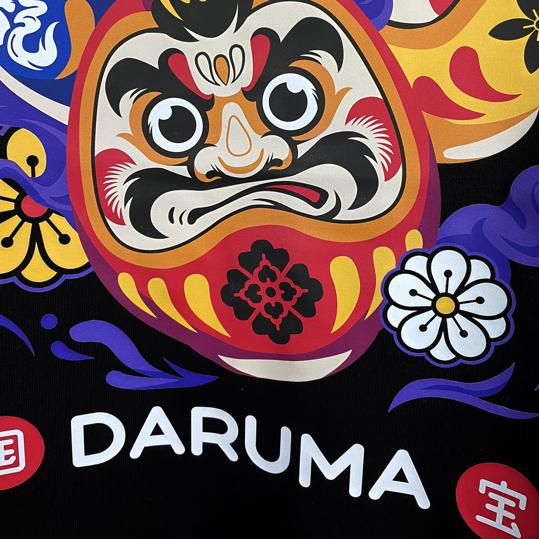 Daruma - a close-up of a graphic design of Japanese drama doll, printed on the front of a Japanese style black heavyweight T-shirt-1