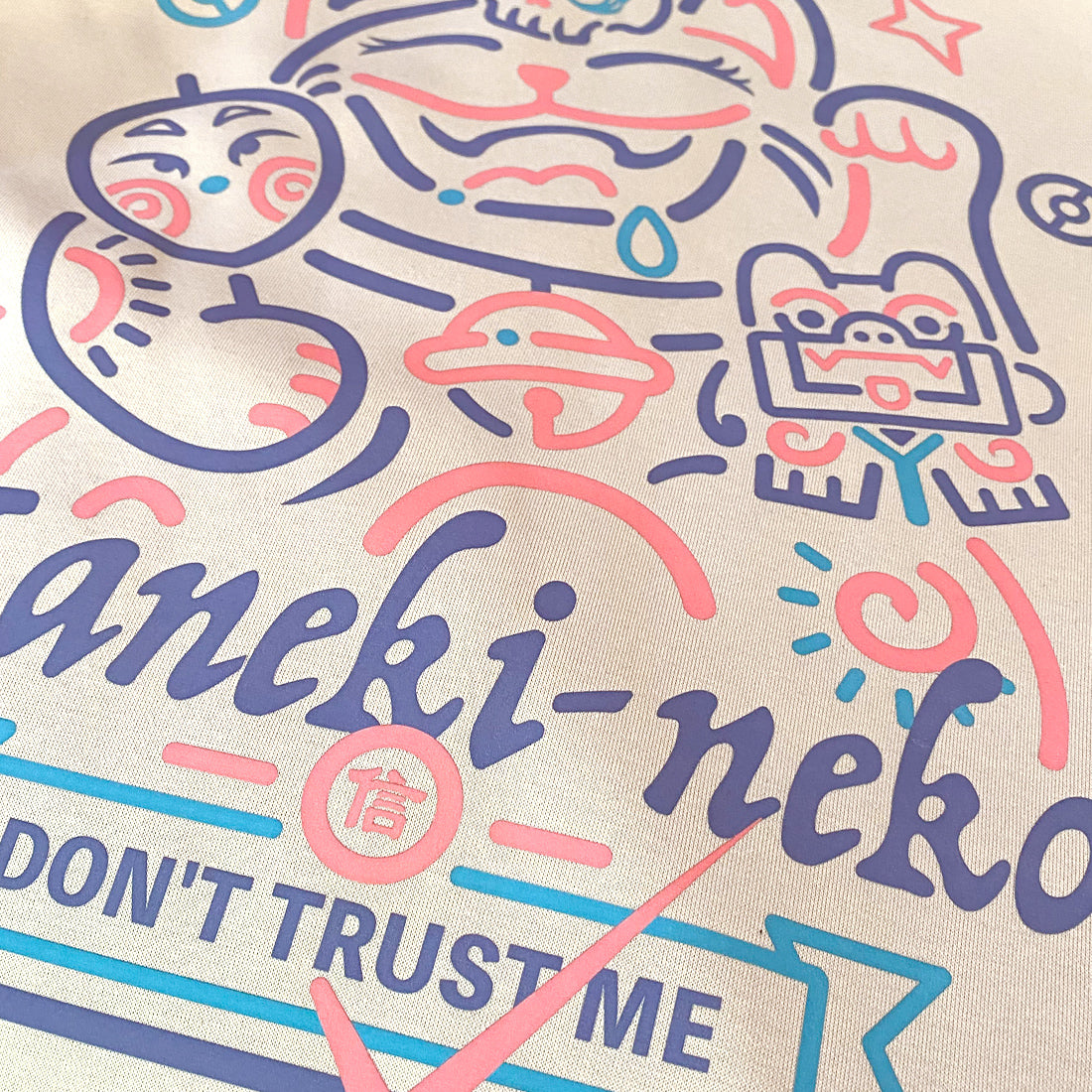 Not to believe in luck- a close-up of a Japanese luck cat design printed on the front of a khaki sweatshirt-2