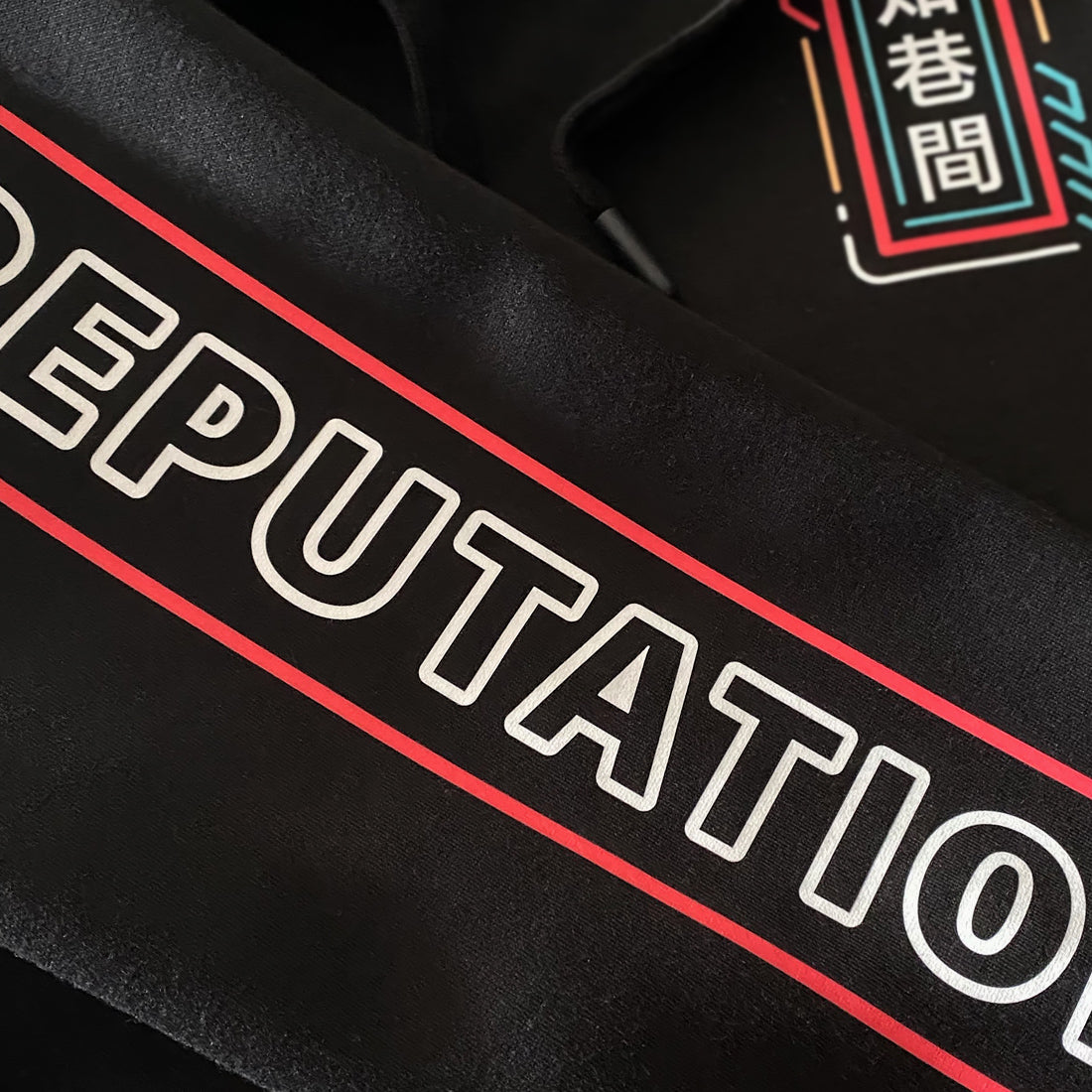 Neon - a close-up of the graphic design on a Japanese style black hoodie sleeve