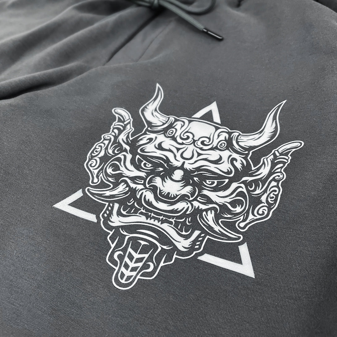 Sins Exist In Human Minds  - a close-up of a design inspired by Japanese Oni masks, printed on the left of a Japanese style dark grey sweatpants 